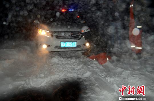 圖為消防人員跪在雪地里用鐵鍬鏟雪救援被困車輛。　李江江　攝